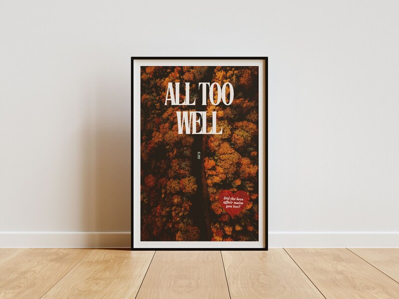 May include: A framed print with a black frame and a white background. The print features an aerial view of a road through a forest with fall foliage. The text "ALL TOO WELL" is printed in white at the top of the print. The text "Did the love affair make you feel?" is printed in red at the bottom of the print.