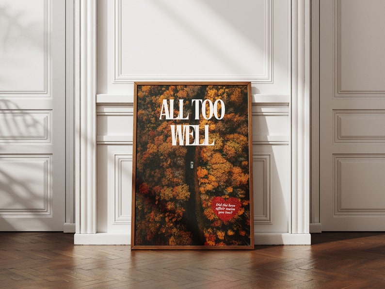 May include: A framed print with the text "ALL TOO WELL" in white letters on a background of an aerial view of a road through a forest with autumn leaves in shades of orange, yellow, and red. The text "Did the love affair mean you back?" is in red letters at the bottom of the print.