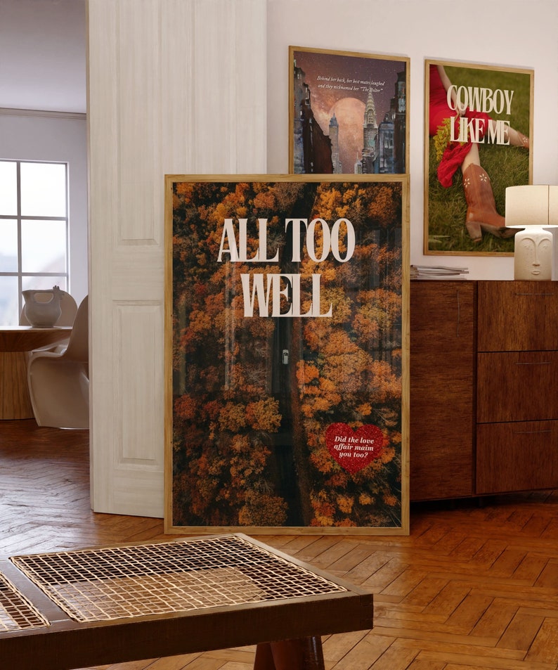 May include: A framed poster with the text "ALL TOO WELL" in white letters on a background of an aerial view of a road through a forest with autumn leaves. The text "Did the love affair ruin you too?" is in red letters at the bottom of the poster.