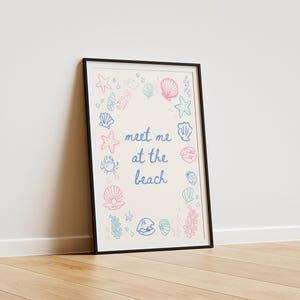 May include: A framed print with a white background and a blue and pink outline of seashells, starfish, and seaweed. The text "Meet me at the beach" is written in blue cursive.