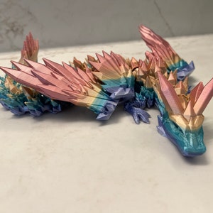 May include: A multi-colored, crystal-like dragon figurine with a rainbow gradient. The dragon is made of plastic and has a detailed, textured surface.