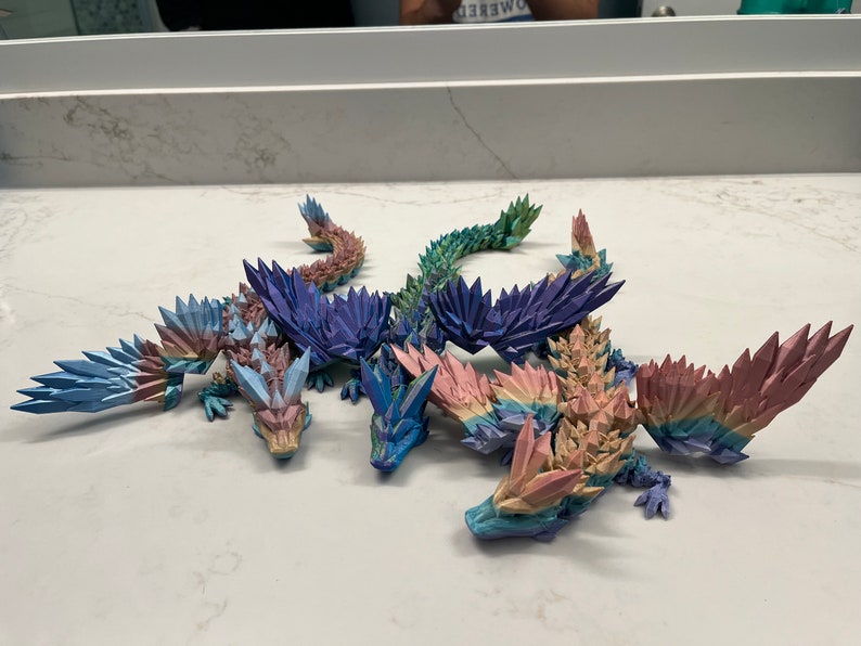 May include: Four origami dragons made of paper, each with a different color scheme. The dragons are arranged in a group, with their wings spread out. The dragons are made of paper and have a shiny, iridescent finish.