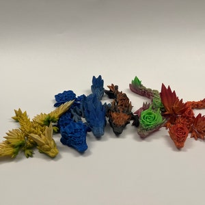 May include: A set of six small, colorful dragon figurines. The dragons are made of a textured material and have a variety of colors, including blue, green, red, orange, yellow, and purple.