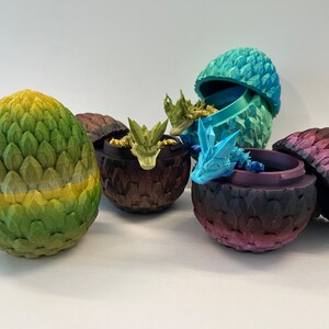 May include: Five dragon eggs, each with a different color and design. The eggs are made of a textured material and have a realistic look. Some of the eggs are open, revealing a small dragon inside.