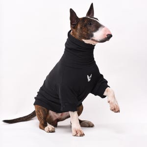 May include: A black turtleneck sweater for dogs with a small white dog silhouette on the chest. The sweater is made of a soft, comfortable material and is perfect for keeping your dog warm in the winter.