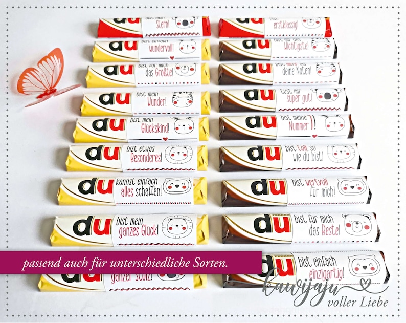 Puede incluir: Una colecci&oacute;n de barras de chocolate con envoltorios personalizados que presentan varias frases en alem&aacute;n e ilustraciones de animales lindos. Los envoltorios son blancos con texto rojo y negro, y las barras de chocolate tienen embalaje amarillo y marr&oacute;n. Se ve una mariposa de papel.