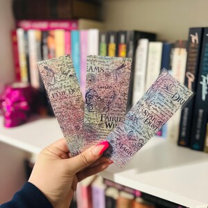 May include: Three whimsical bookmarks with fairy and butterfly illustrations. Each bookmark features a different design with text including "Pixie Dust", "Dreams", and "Star Dust". The bookmarks have a watercolor effect with pastel colors.