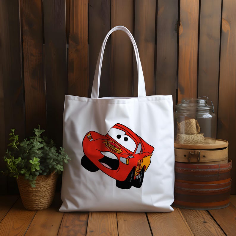 May include: White canvas tote bag with a red cartoon car printed on the front. The car has a smiling face and the words "Lightning McQueen" printed on the side.