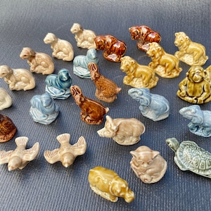 May include: A collection of 20 miniature ceramic animal figurines. The figurines are painted in various colors, including brown, blue, green, and white. The figurines depict a variety of animals, including a turtle, a hippopotamus, a pig, a rabbit, an owl, a bird, an elephant, a monkey, and a cat.