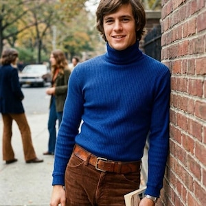 May include: A man in a blue turtleneck jumper, brown corduroy trousers, and a brown leather belt with a silver buckle. He leans against a brick wall, holding a book. The image has a vintage aesthetic.