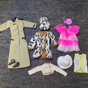 May include: A set of doll clothes including a tan trench coat, a leopard print coat, a pink tulle dress, a white cowboy hat, a white lace vest, a white jacket, and a brown fur hat.