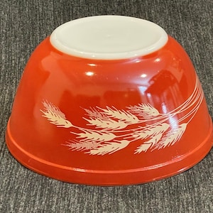Puede incluir: Un cuenco rojo vintage con interior blanco y diseño de espigas de trigo. El cuenco está hecho de un material brillante y es ideal para la cocina. El cuenco tiene aproximadamente 20 cm de diámetro.