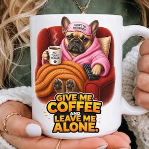 Könnte beinhalten: Weiße Keramik-Tasse mit einem Cartoon-Französisch-Bulldogge in einem rosa Bademantel und einer Augenmaske, die eine Kaffeetasse und eine Fernbedienung hält. Die Tasse trägt den Text "GIVE ME COFFEE AND LEAVE ME ALONE."