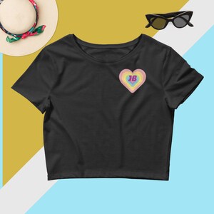 May include: Black cropped t-shirt with a rainbow heart design and the number "18" in the center.