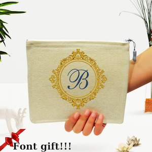 Può includere: Un astuccio in tela beige con un ornato emblema color oro e la lettera blu "B" al centro. L'astuccio è tenuto in mano. Il testo "Font gift!!!" è in basso.