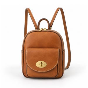 May include: A tan leather backpack featuring a front pocket with a gold-toned metal turn-lock closure, a top handle, and two adjustable shoulder straps. The bag has a main zippered compartment with dual gold-toned zipper pulls and white stitching.