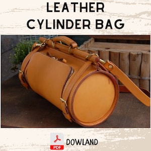 Puede incluir: Un bolso cilíndrico de cuero marrón con un asa superior y una correa para el hombro. El bolso tiene un bolsillo con cremallera y herrajes dorados. El texto "LEATHER CYLINDER BAG" está en la parte superior de la imagen.