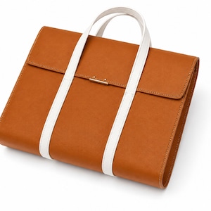 Peut inclure: Une serviette en cuir marron avec une poignée blanche et des sangles blanches. La serviette a une fermeture à rabat avec une barre métallique dorée. Le sac est rectangulaire et semble être en cuir de haute qualité.