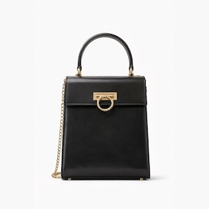 May include: Black leather handbag with a gold-tone chain strap and top handle. The rectangular bag features a gold ring clasp closure and gold hardware accents. The bag is a classic design, suitable for various occasions.