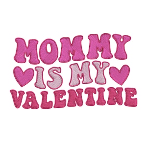 May include: Embroidered patch with the phrase "MOMMY IS MY VALENTINE" in pink thread. The text is in a bubble letter style with a heart symbol on each side of "IS MY". The patch is on a white background.
