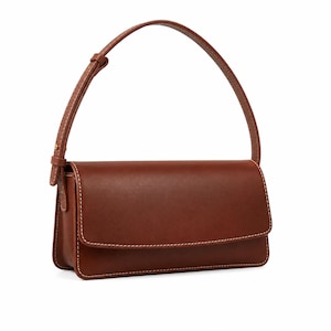 May include: A structured brown leather shoulder bag with a rectangular silhouette, a fold-over flap closure, and a single adjustable strap. The bag features visible white contrast stitching along the edges and a smooth, matte finish throughout.
