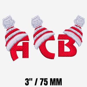 Puede incluir: Letras bordadas A, C y B, cada una coronada con un gorro de invierno a rayas rojas y blancas con un pompón blanco. Las letras son rojas y los sombreros miden aproximadamente 7,6 cm de alto.