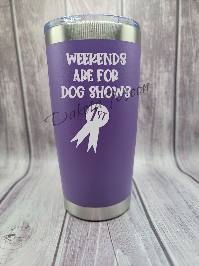 Op de afbeelding: Een paarse roestvrijstalen beker met een wit ontwerp met de tekst "Weekends are for dog shows" en een wit lint met "1st" erop.