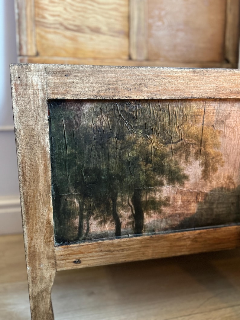 Peut inclure: Banc en bois avec une peinture de paysage sur le panneau avant. La peinture repr&eacute;sente des arbres dans une for&ecirc;t avec une palette de couleurs sourdes de verts, de bruns et de touches de rose. Le banc a un cadre en bois brun clair vieilli.