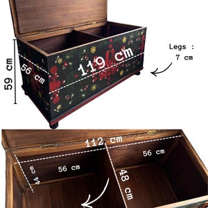 May include: A wooden storage chest with a black exterior featuring red and yellow floral patterns. The chest measures 119 cm long, 56 cm deep, and 59 cm high, with 7 cm legs. The interior has a removable divider, measuring 112 cm by 56 cm.