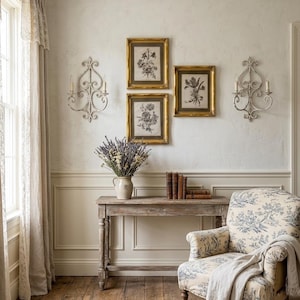 Puede incluir: Un interior acogedor con una consola de madera, un jarrón con lavanda y grabados botánicos enmarcados. Un sillón estampado y apliques de pared realzan el encanto vintage de la habitación. La habitación tiene suelos de madera y una paleta de colores neutros.