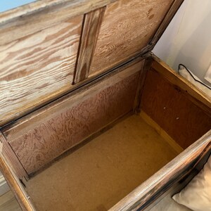 Peut inclure: Un coffre en bois ancien ouvert avec un couvercle &agrave; charni&egrave;re. Le coffre est en bois brun clair avec des motifs de grain visibles. L'int&eacute;rieur est doubl&eacute; de bois de couleur plus claire. Le coffre semble vide.