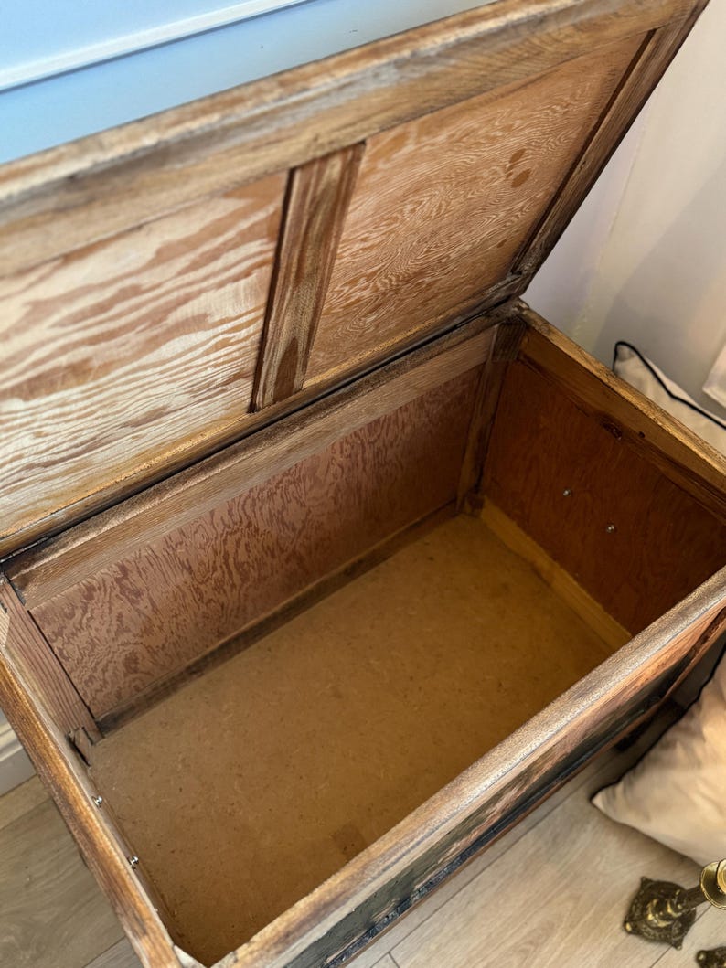 Peut inclure: Un coffre en bois ancien ouvert avec un couvercle &agrave; charni&egrave;re. Le coffre est en bois brun clair avec des motifs de grain visibles. L'int&eacute;rieur est doubl&eacute; de bois de couleur plus claire. Le coffre semble vide.
