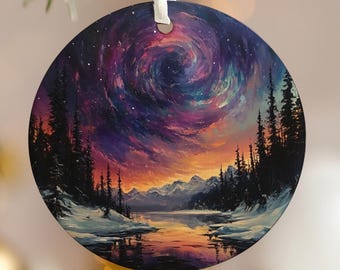 May include: Round Christmas ornament featuring a landscape painting of a swirling galaxy over a snowy forest and lake. The ornament has a white ribbon for hanging. The artwork includes shades of purple, orange, and blue.
