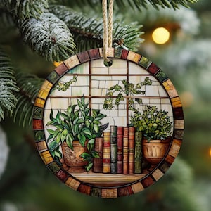 Könnte beinhalten: Runder Weihnachtsbaumschmuck mit einem Buntglasdesign, das ein Fenster mit Topfpflanzen und Büchern zeigt. Das Fenster ist in einem bunten Mosaik gerahmt.