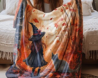 Könnte beinhalten: Eine farbenfrohe Decke mit einer Hexe in einem schwarzen Kleid und Hut, mit einer schwarzen Katze, in einer Waldkulisse mit Herbstlaub. Die Decke hat ein weiches, gemütliches Aussehen, perfekt, um jedem Raum einen Hauch von Laune zu verleihen.