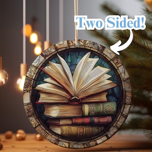Peut inclure: Une boule de Noël ronde et double face avec un motif de vitrail représentant un livre ouvert avec une pile de livres en dessous. La boule est entourée d'une bordure décorative.