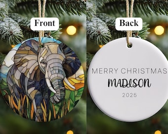 May include: A round Christmas ornament with an elephant design on the front. The elephant is depicted in a stained-glass style with shades of gray, brown, and blue. The back of the ornament reads "MERRY CHRISTMAS MADISON 2025".