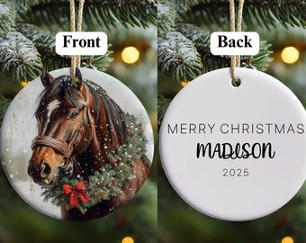May include: A round Christmas ornament with a horse portrait on the front. The horse is brown with a wreath and red bow. The back of the ornament says "MERRY CHRISTMAS MADISON 2025". The ornament hangs from a twine string.