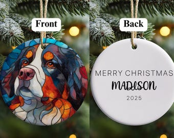 May include: A circular Christmas decoration featuring a stained-glass effect dog portrait. The reverse side is white, inscribed with "MERRY CHRISTMAS MADISON 2025". It is suspended by a brown string, ideal for festive display.