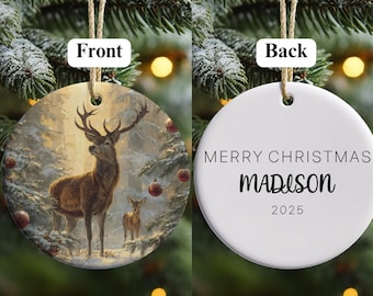 May include: A round Christmas ornament with a deer scene on the front and text on the back. The front features a brown deer and fawn in a snowy forest with red ornaments. The back says "MERRY CHRISTMAS" and "MADISON 2025".