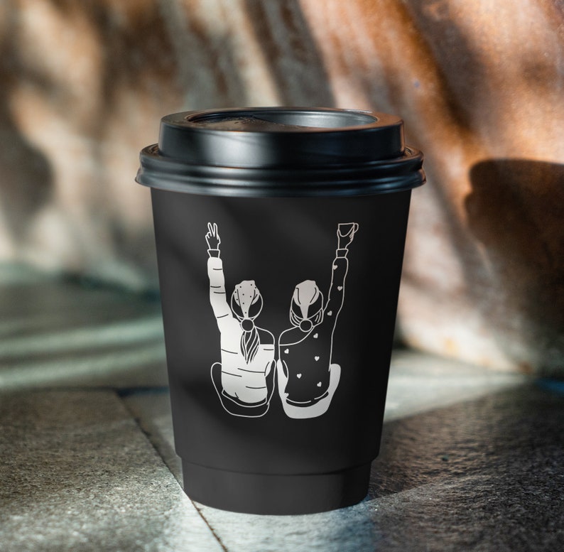 K&ouml;nnte beinhalten: Schwarzer Coffee-to-go-Becher mit einer wei&szlig;en Grafik von zwei Personen, die die Arme in die Luft strecken. Die Grafik zeigt zwei Personen mit dem R&uuml;cken zum Betrachter.