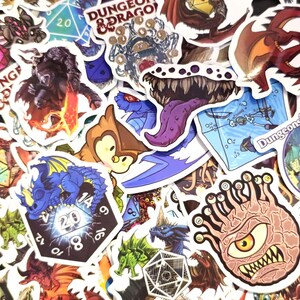 May include: A collection of colorful fantasy-themed stickers featuring dragons, dice, and monsters. The stickers have various designs, including a blue dragon, a red dragon, and a creature with multiple eyes. Some stickers have the text "Dungeon & Dragon".