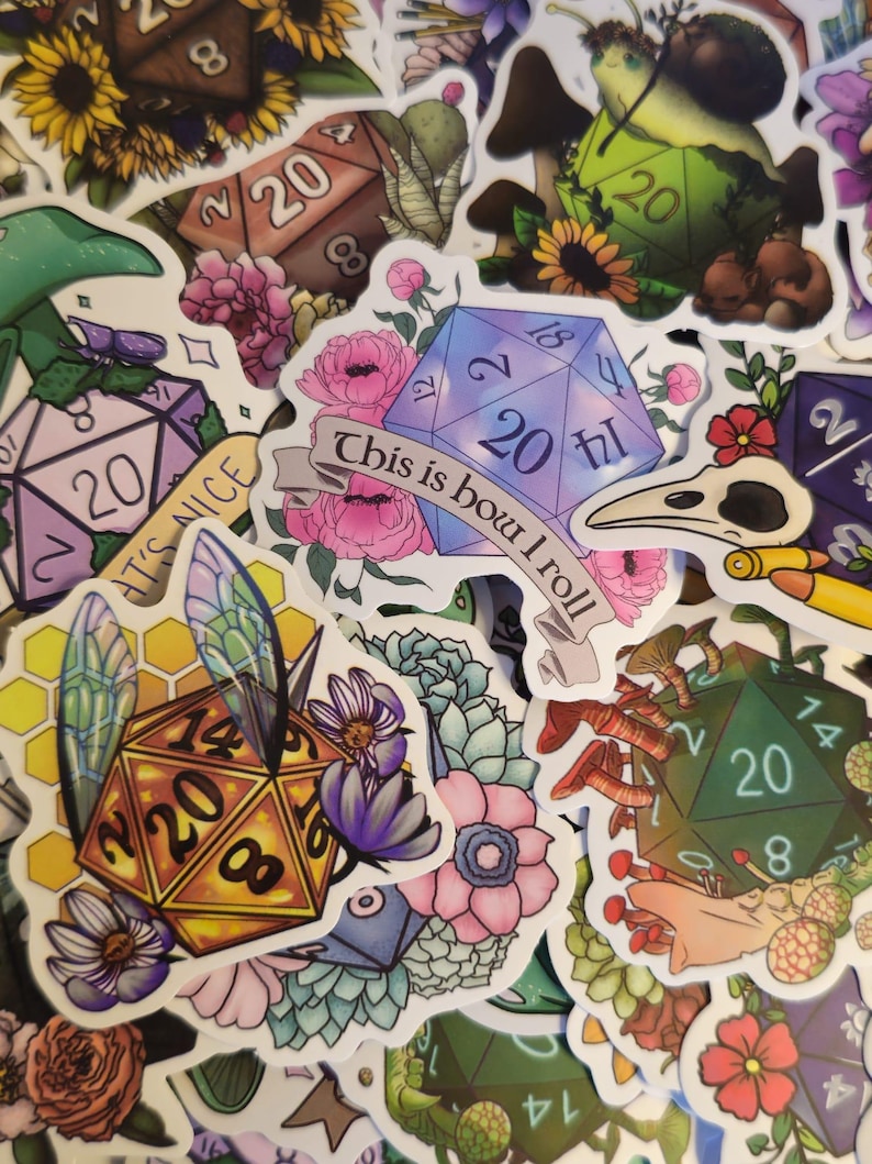 May include: A collection of colorful stickers featuring dice, flowers, mushrooms, and insects. Some stickers have the number 20 on them, and one reads "This is how I roll."