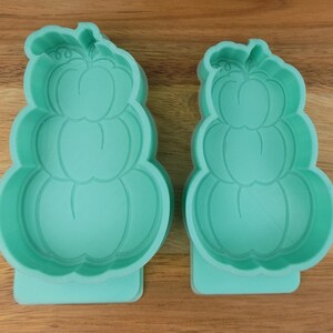Peut inclure: Deux moules en plastique vert en forme de pile de citrouilles. Les moules sont de tailles différentes.