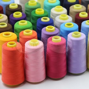 May include: A collection of spools of colourful thread, including orange, pink, red, purple, blue, green, yellow, and brown. The spools are arranged in a semi-circle, with the ends of the thread visible.