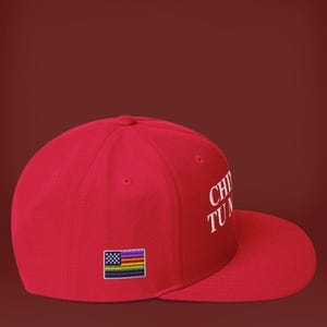 K&ouml;nnte beinhalten: Rote Baseballkappe mit einer wei&szlig;en Stickerei, die "CHOP TU MOUTH" lautet. Die Kappe hat einen kleinen Regenbogenflaggen-Patch auf der Vorderseite.
