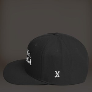 K&ouml;nnte beinhalten: Schwarze und wei&szlig;e bestickte Baseballkappe mit dem Text "YOGA" an der Seite. Die Kappe hat einen schwarzen Schirm und eine schwarze Krone. Die Kappe hat ein kleines wei&szlig;es besticktes "X" auf der R&uuml;ckseite.