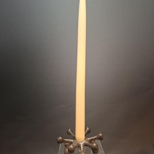 Op de afbeelding: Een witte kaars staat in een zwarte metalen kandelaar met een stervormig ontwerp. De kandelaar staat op een heldere acrylbasis.