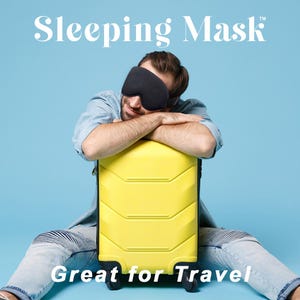 May include: A person wearing a black sleeping mask, leaning on a yellow suitcase. The image has the text "Sleeping Mask" and "Great for Travel" on a blue background. The suitcase has four wheels.