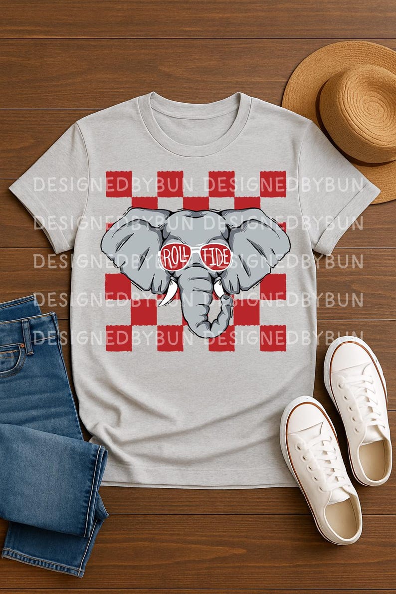 May include: A light gray t-shirt featuring a cartoon elephant wearing sunglasses with the text "Roll Tide." The elephant is set against a red and white checkered background. The words "Designed by Bun" are printed around the top of the shirt.